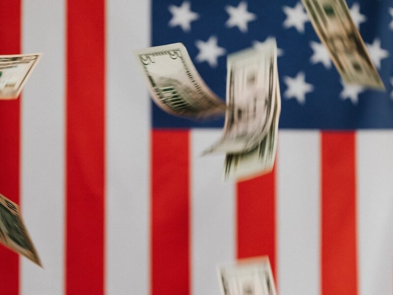 National flag of United States of America on background and dollars falling down