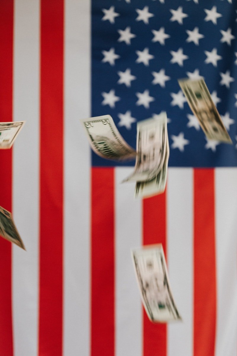 National flag of United States of America on background and dollars falling down