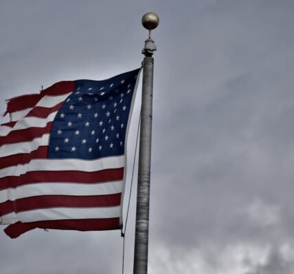 an american flag flying in the wind on a cloudy day