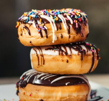 three chocolate-coated donuts with sprinkles