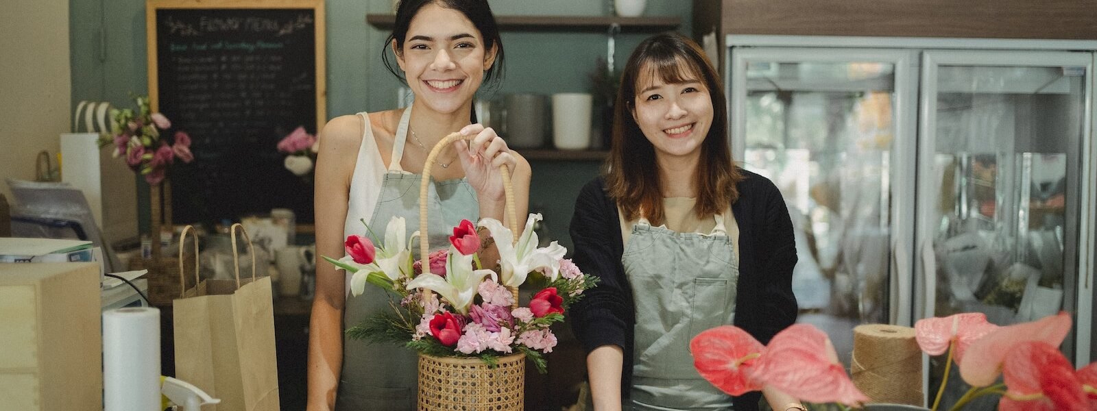 Smiling florists standing at counter in floristry shop