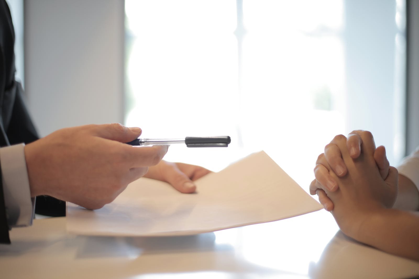 Crop businessman giving contract to woman to sign